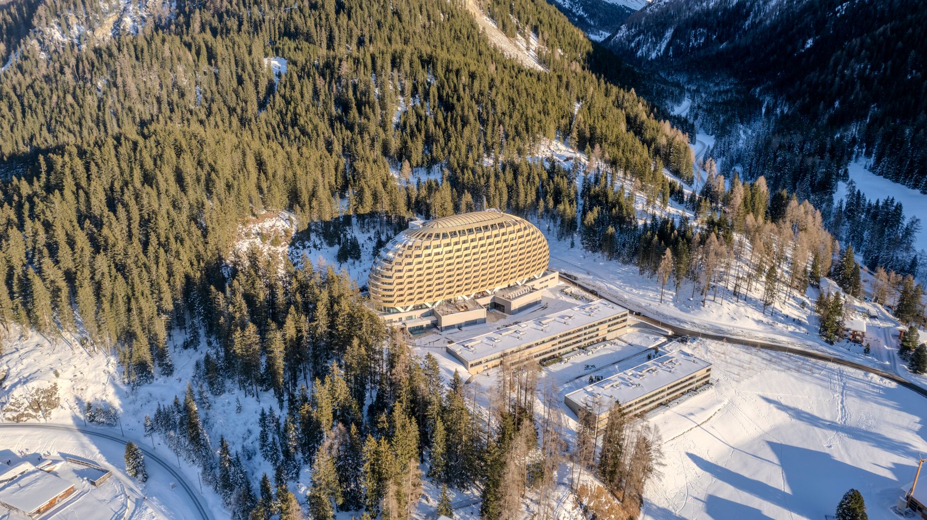 Stunning aerial view of a modern hotel surrounded by snowy forests in the Swiss Alps, Davos. — photograph by Ollie Craig on Pexels