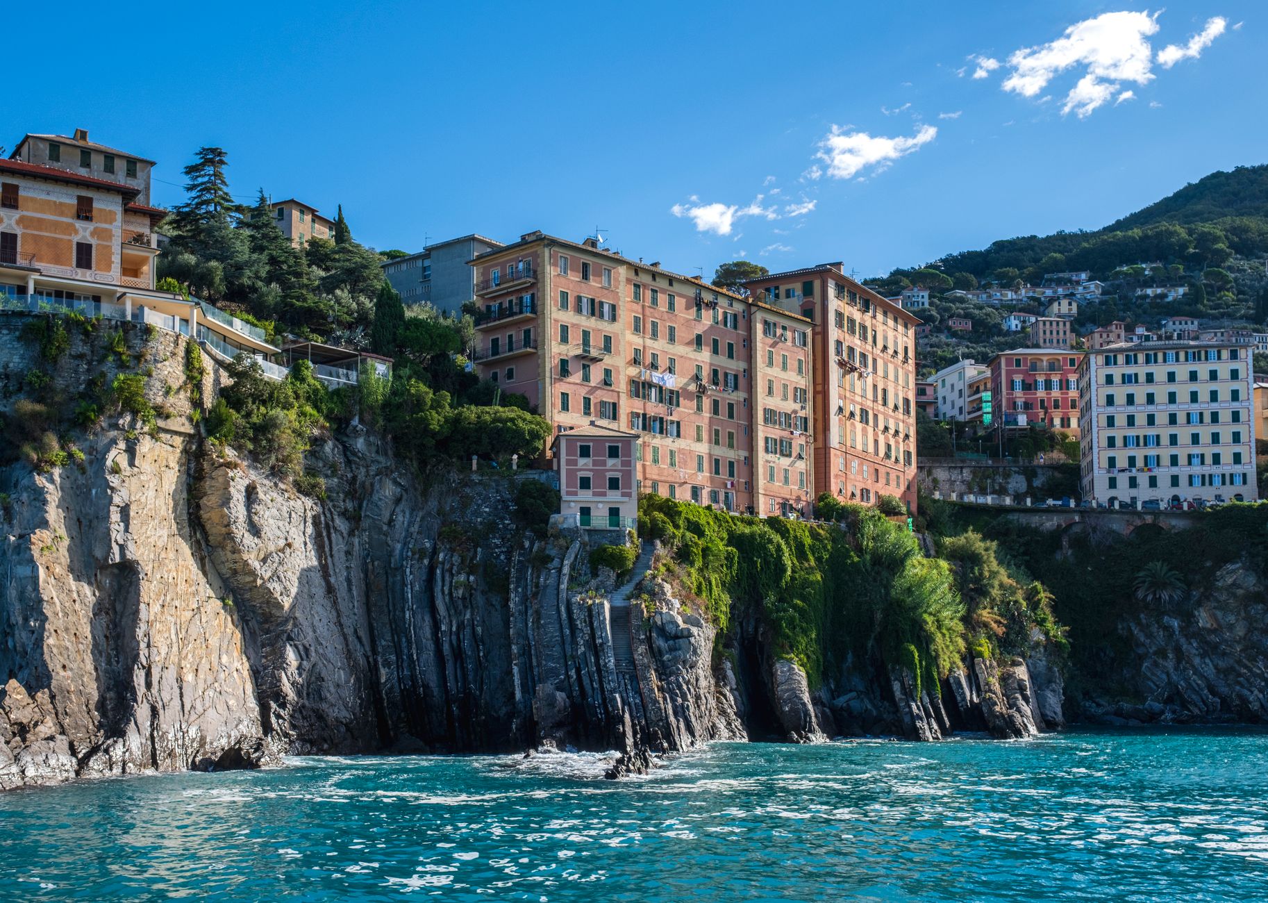 Charming old buildings atop rocky cliffs along Italy's Ligurian coastline on a sunny day. — photograph by pierre matile on Pexels